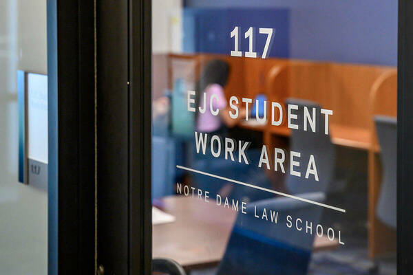 A glass door in the Notre Dame Law School leads to room 117, the EJC Student Work Area
