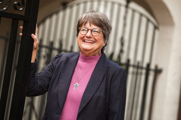 Death penalty abolitionist Sister Helen Prejean stands outdoors with one hand on an iron gate