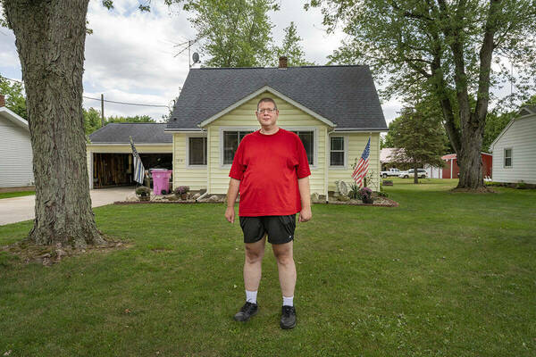 Andrew Royer, exonerated from his Elkhart wrongful conviction, stands in the front yard of yellow house on a partly cloudy day