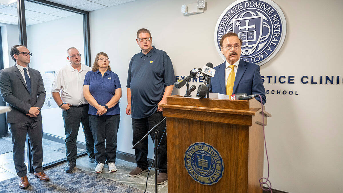 Jimmy Gurulé stands at podium for press conference with Andrew Royer, exonerated from his Elkhart wrongful conviction, and three other individuals to his left